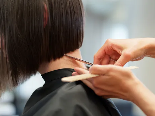 Friseurin schneidet mit Schere und Kamm eine Bob-Kante im Nacken