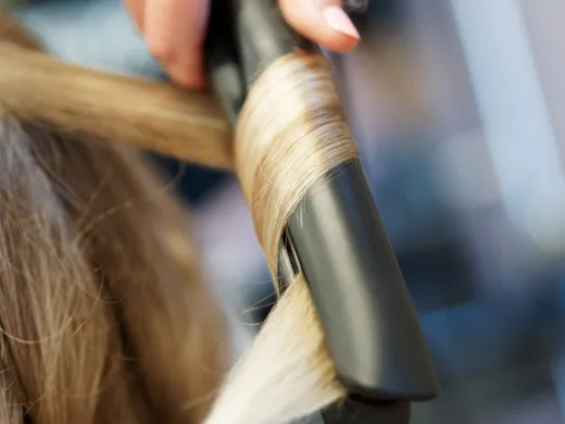 Blonde Strähne wird um einen Lockenstab gelegt